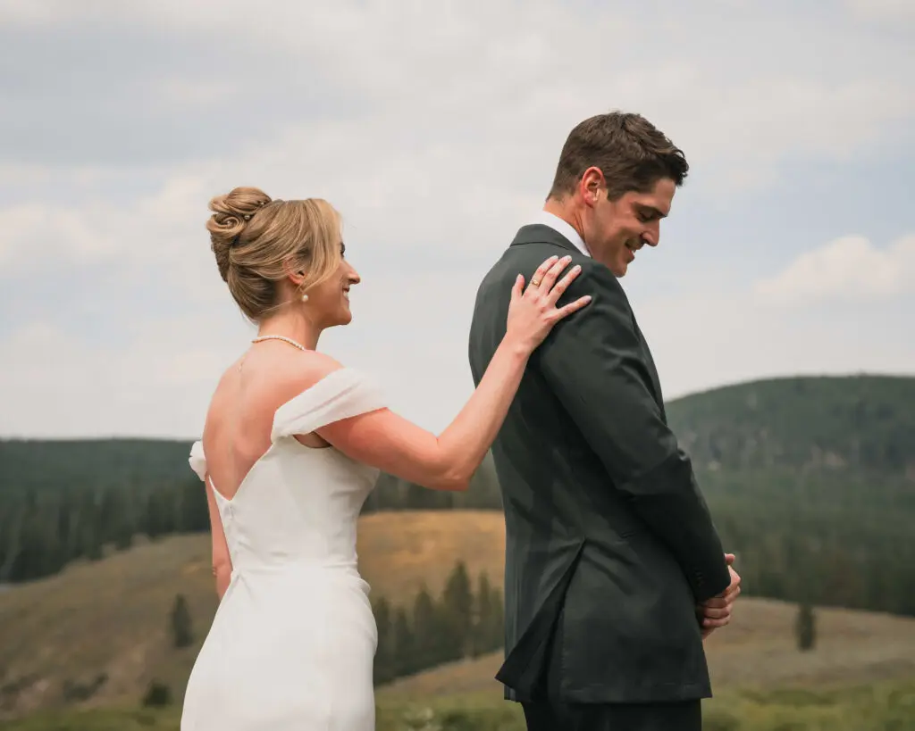 First look moment between bride and groom on hillside with forested mountains and overcast sky - intimate elopement wedding venues in Colorado