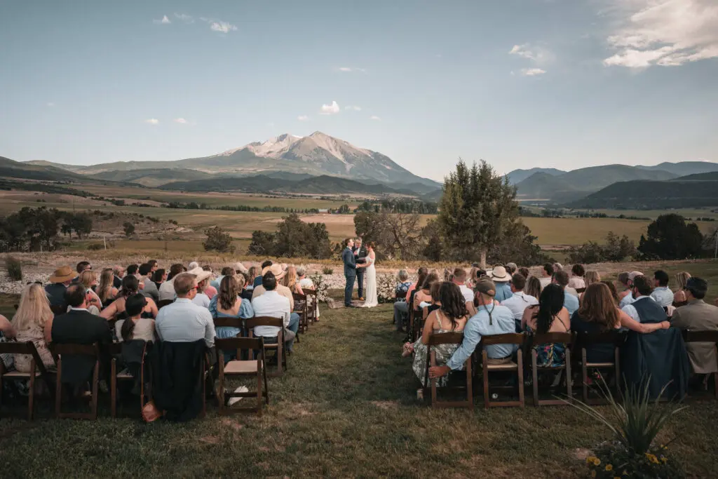 Bride smiling over her groom's shoulder during a golden hour outdoor wedding in Aspen