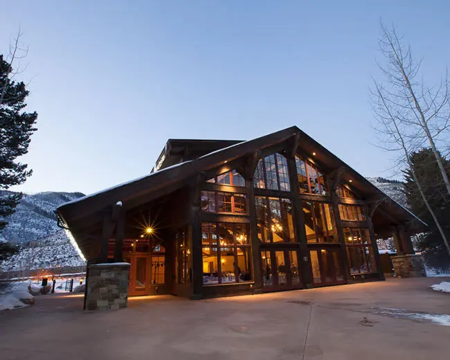 Elegant mountain wedding venue at Donovan Pavilion in Vail, Colorado, featuring a stunning glass and timber lodge with warm lighting and scenic alpine views.