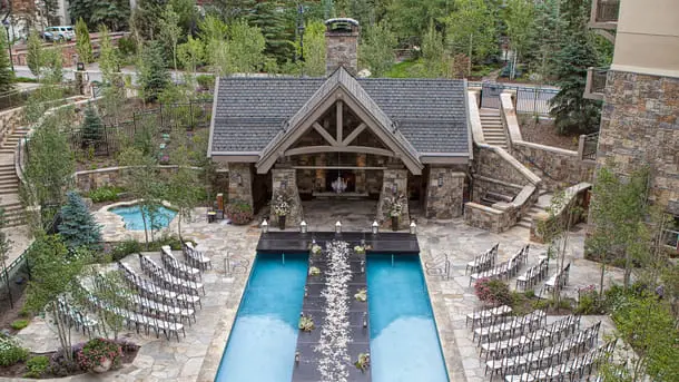 Romantic outdoor wedding ceremony setup by the pool at Four Seasons Resort and Residences Vail, a luxurious Vail Colorado wedding venue surrounded by mountain scenery and lush greenery.