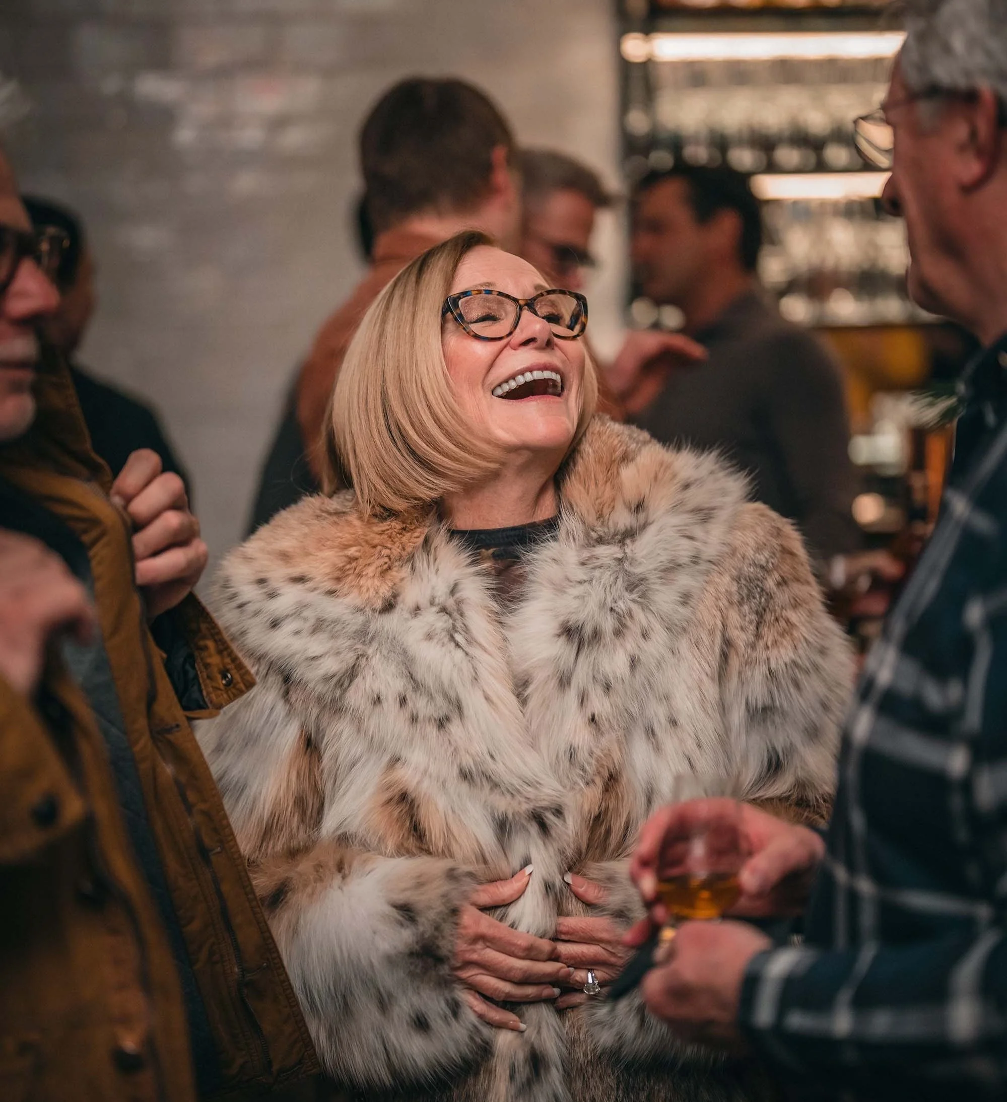 woman laughing holding a wine glass enjoying a party
