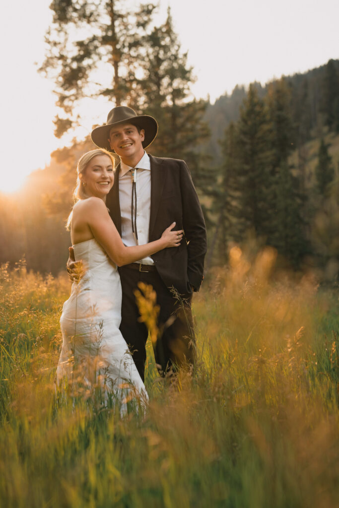 Newlyweds smile as the sun sinks behind the mountains in Aspen, Colorado.