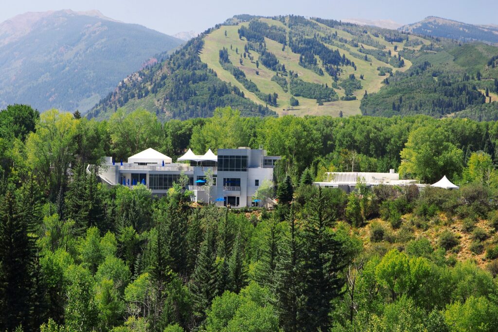 Modern Aspen Meadows Resort nestled in the forest with mountain views in the background.