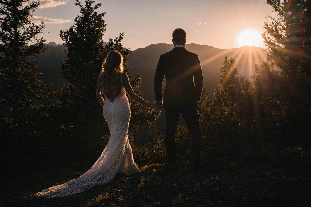 The bride and groom face the distant Aspen mountains, holding each other as they look out over the rugged, tree-lined peaks.
