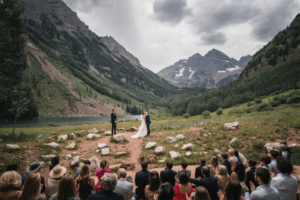Ceremony of bride and groom in Maroon Bells, CO with guests looking on.