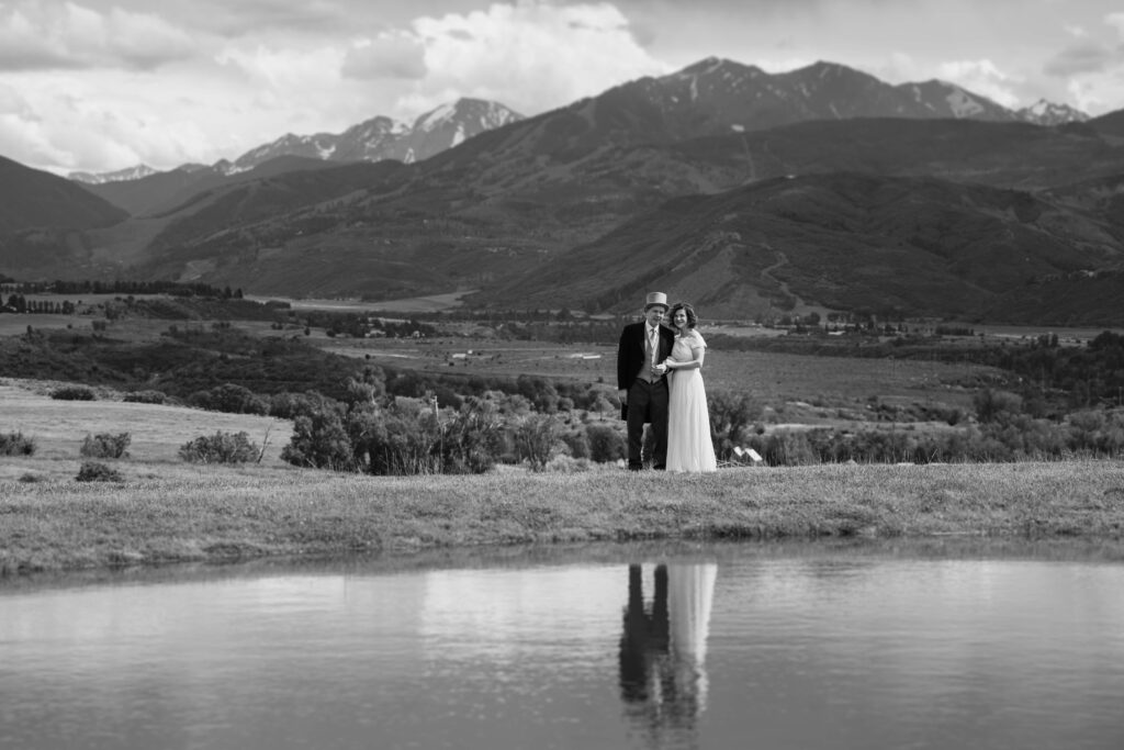 Bride and groom smile in this black and white wide shot of their wedding location in Aspen, CO.