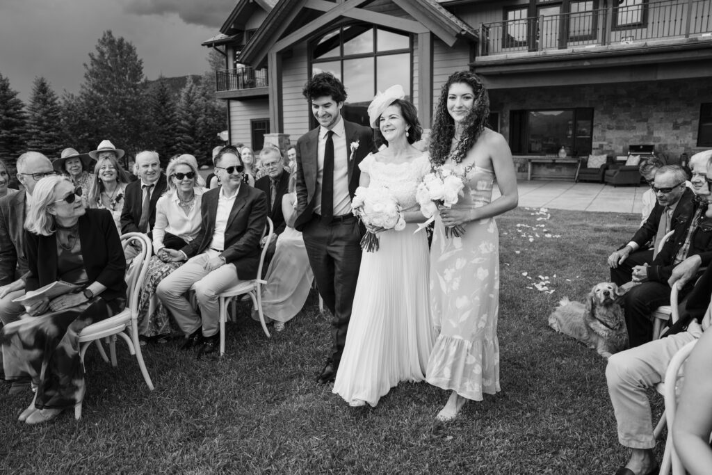 Bride and her two adult children walking together down the aisle at a wedding ceremony