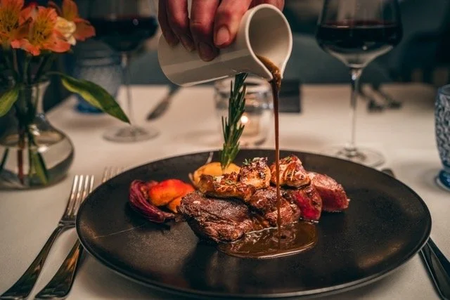 sauce being poured over steak at fine dining aspen colorado restaurant