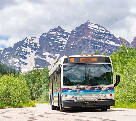 Shuttle navigating a mountain road S curve outside Aspen where drive times run longer than distance suggests