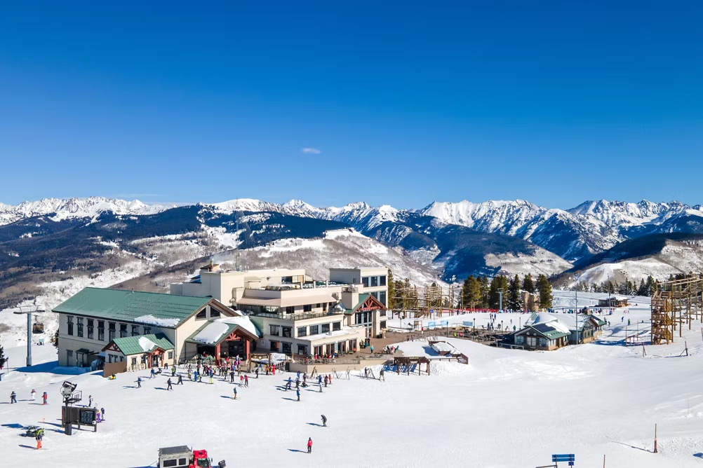Vail Mountain ski resort with skiers, snow-covered slopes, and panoramic Rocky Mountain views on a clear winter day.