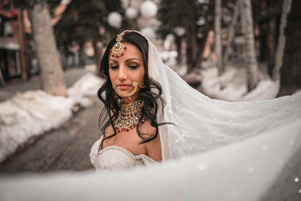 Indian bride wearing ornate bridal jewelry posing and looking down during her portrait session