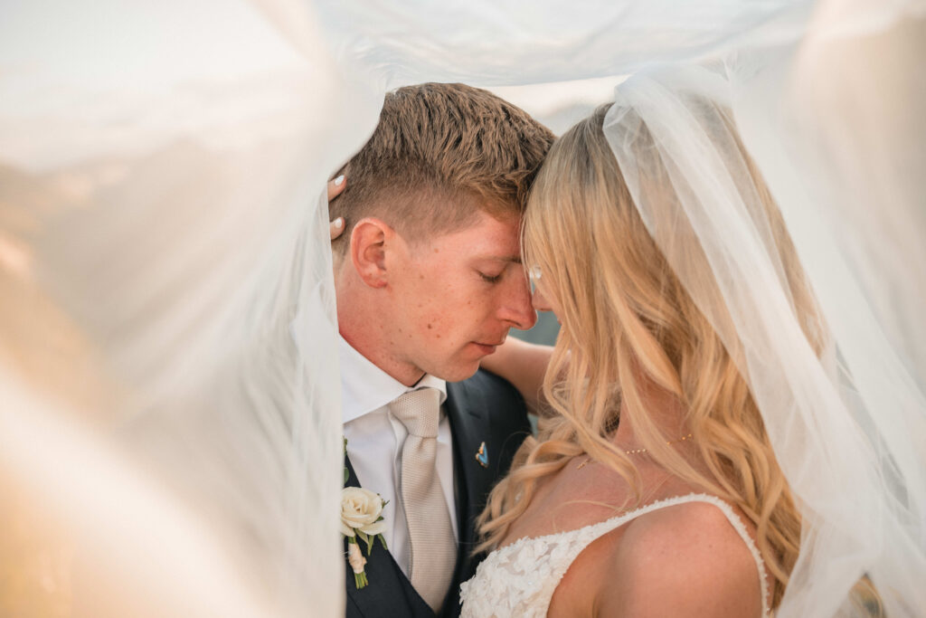 Tight close-up of bride and groom touching foreheads under the bride’s veil, sharing an intimate moment at Maroon Bells.