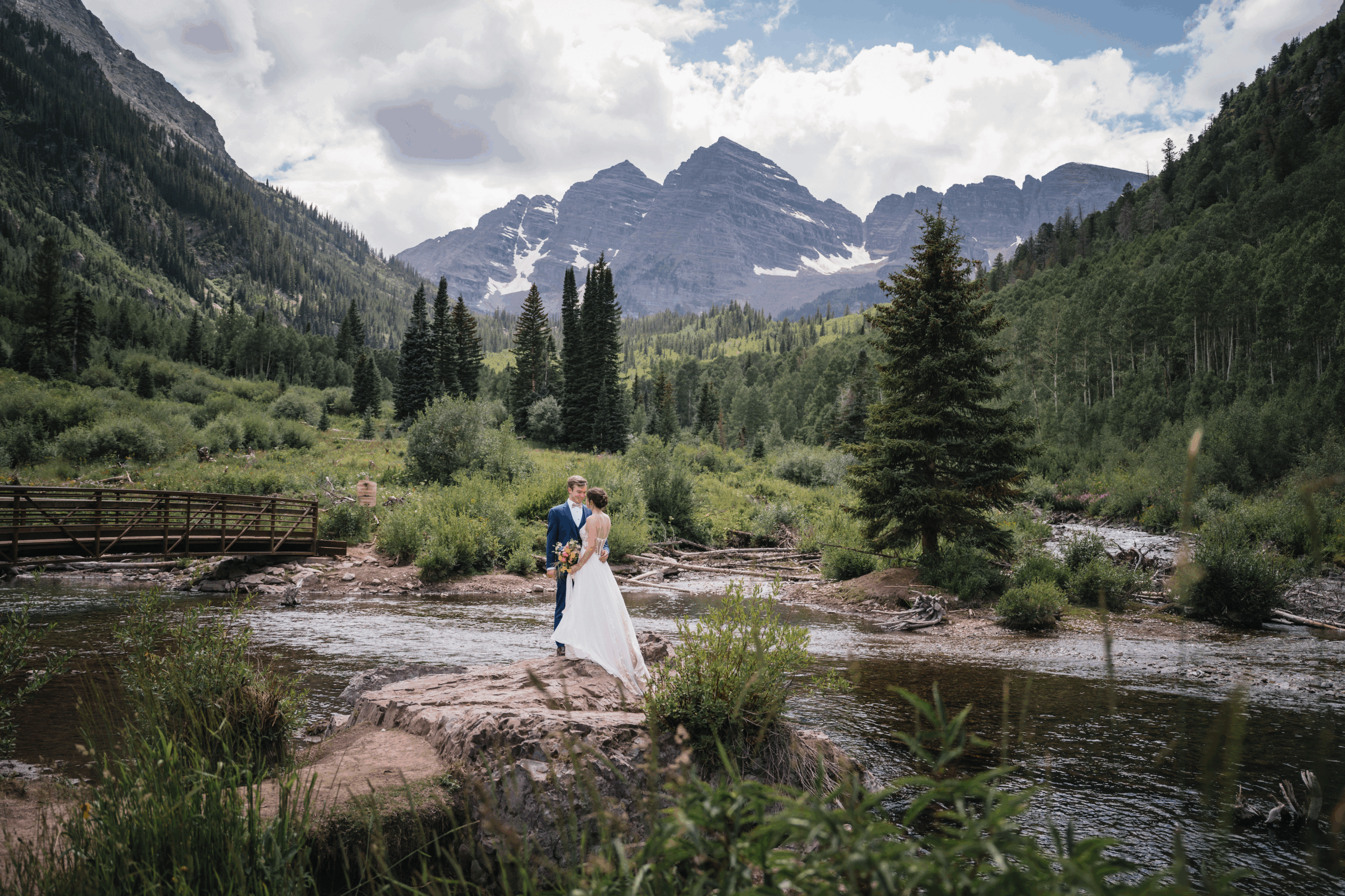Couple getting married at Maroon Bells as they stand before the dramatic mountain peaks and alpine lake surrounded by vibrant scenery.