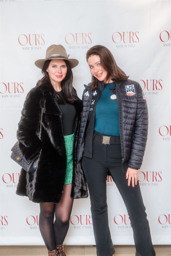 Guest in a faux fur coat and green tweed skirt posing next to an attendee in a US Ski Team puffer jacket, highlighting the intersection of luxury fashion and Aspen mountain culture.