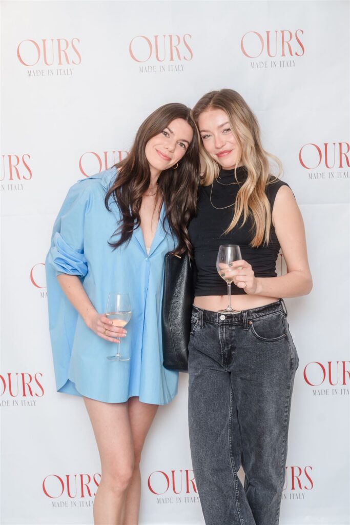 Two women with glasses of wine posing in minimalist, chic attire, showcasing the effortless elegance of a high-end corporate social hour.